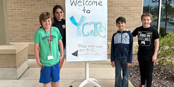 Three children standing in front of a sign that says " welcome to ycare ".
